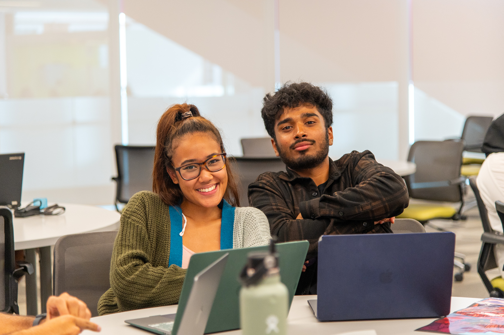 two students sitting at laptops smiling